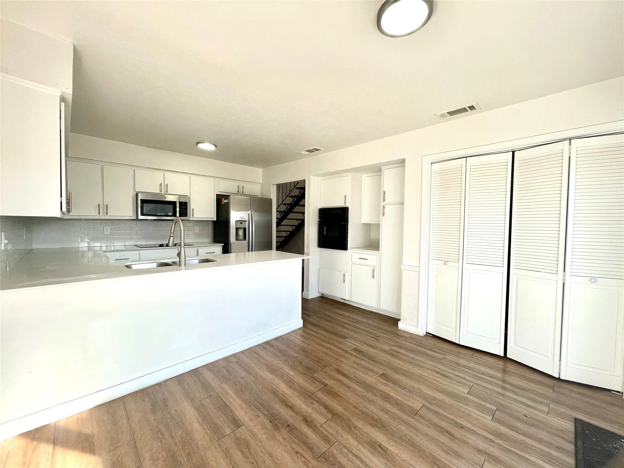 Kitchen featuring kitchen peninsula, stainless steel appliances, backsplash, and white cabinetry