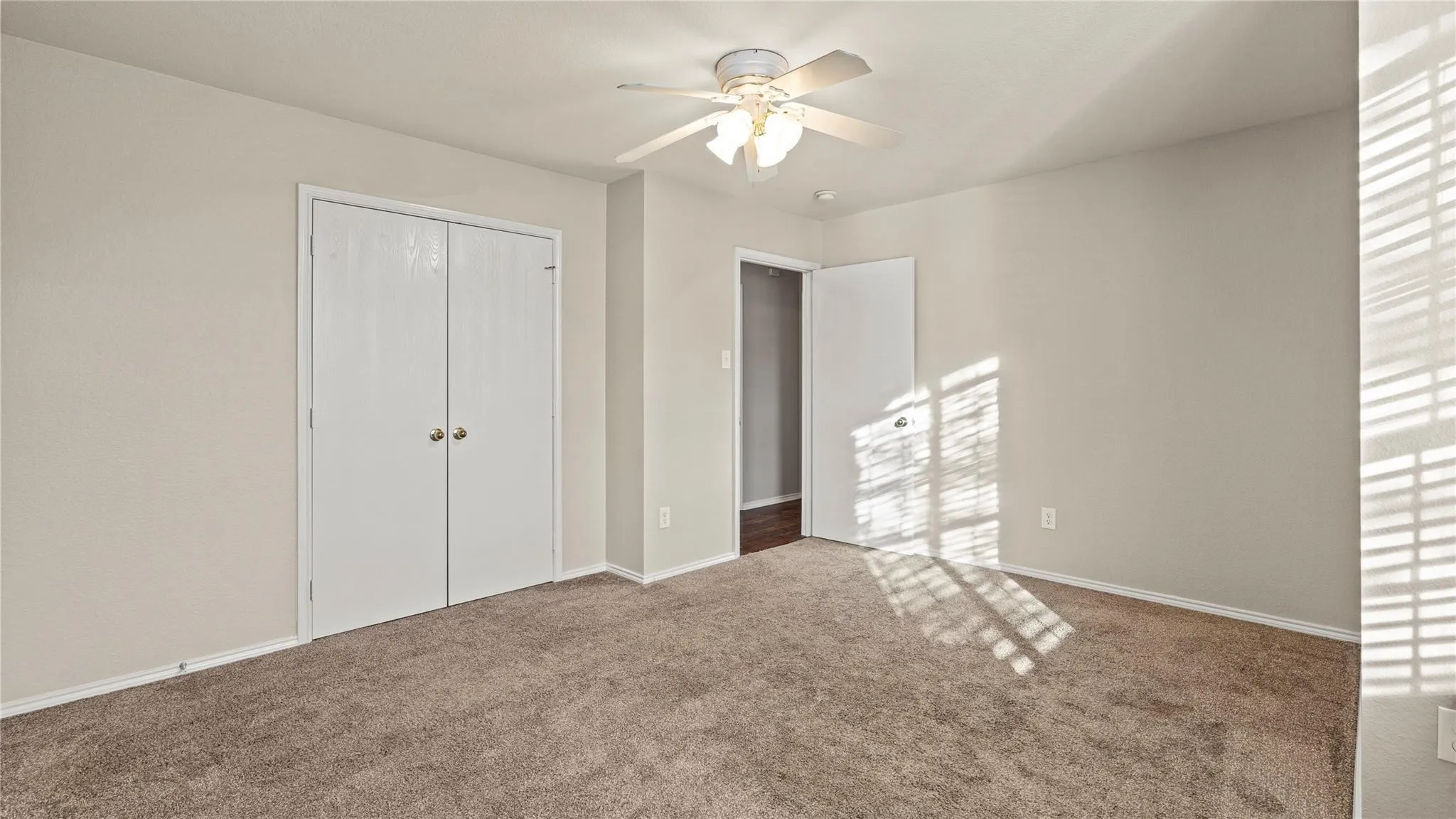 Plush carpeting, neutral wall tones, and a ceiling fan with integrated lighting