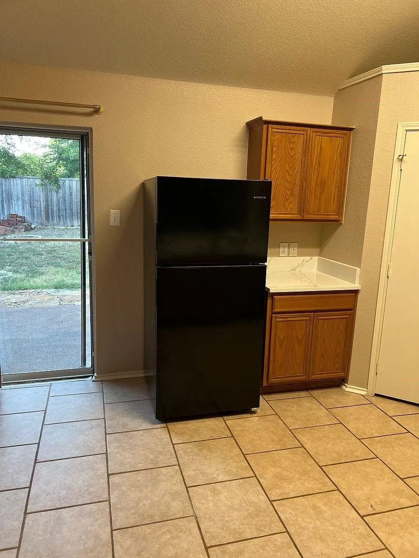 Tile flooring, wood cabinetry, built-in countertop, and glass-paneled exterior door