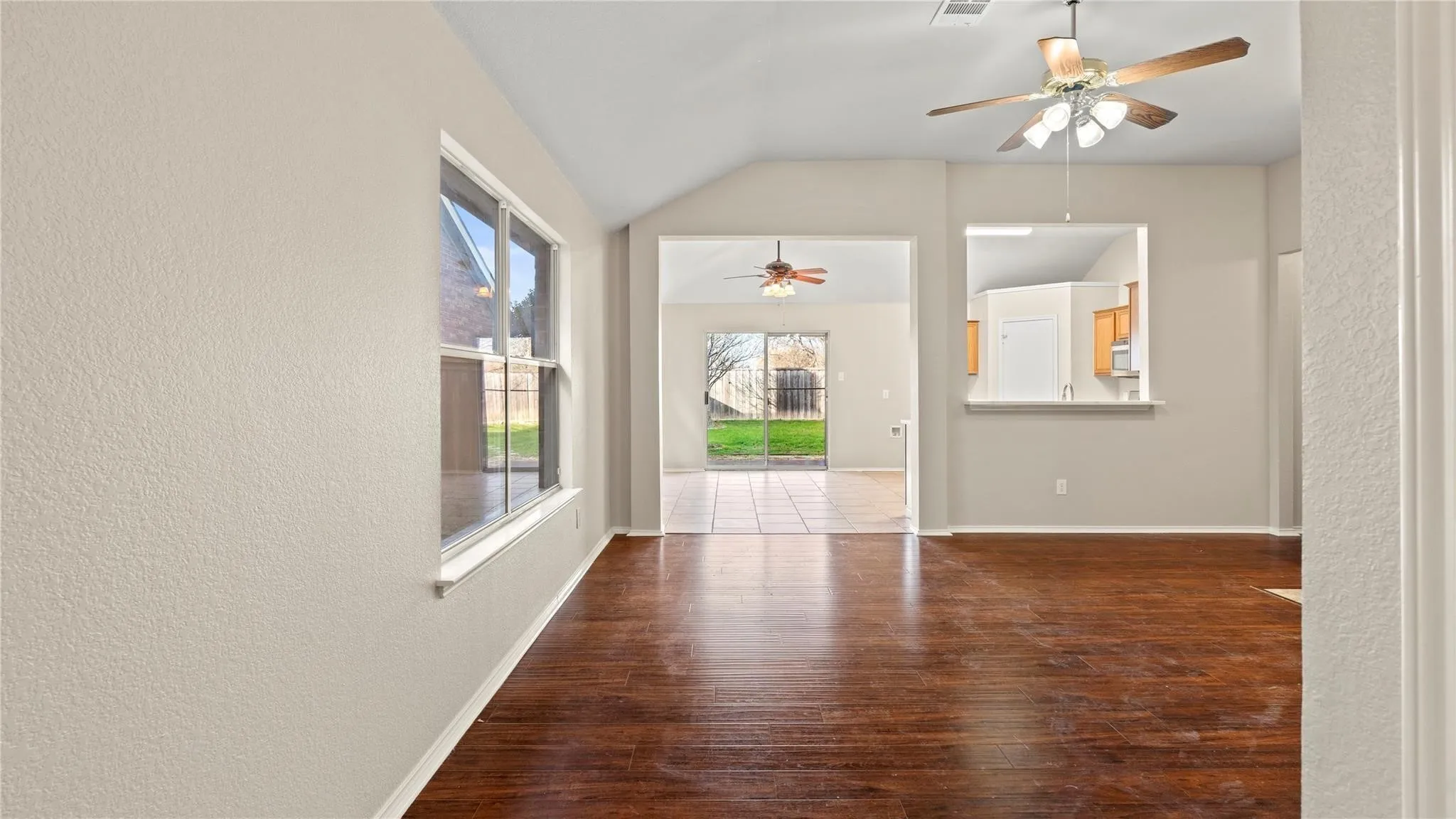 Vaulted ceiling, wood-finish flooring, interior windows, pass-through opening, and ceiling fans