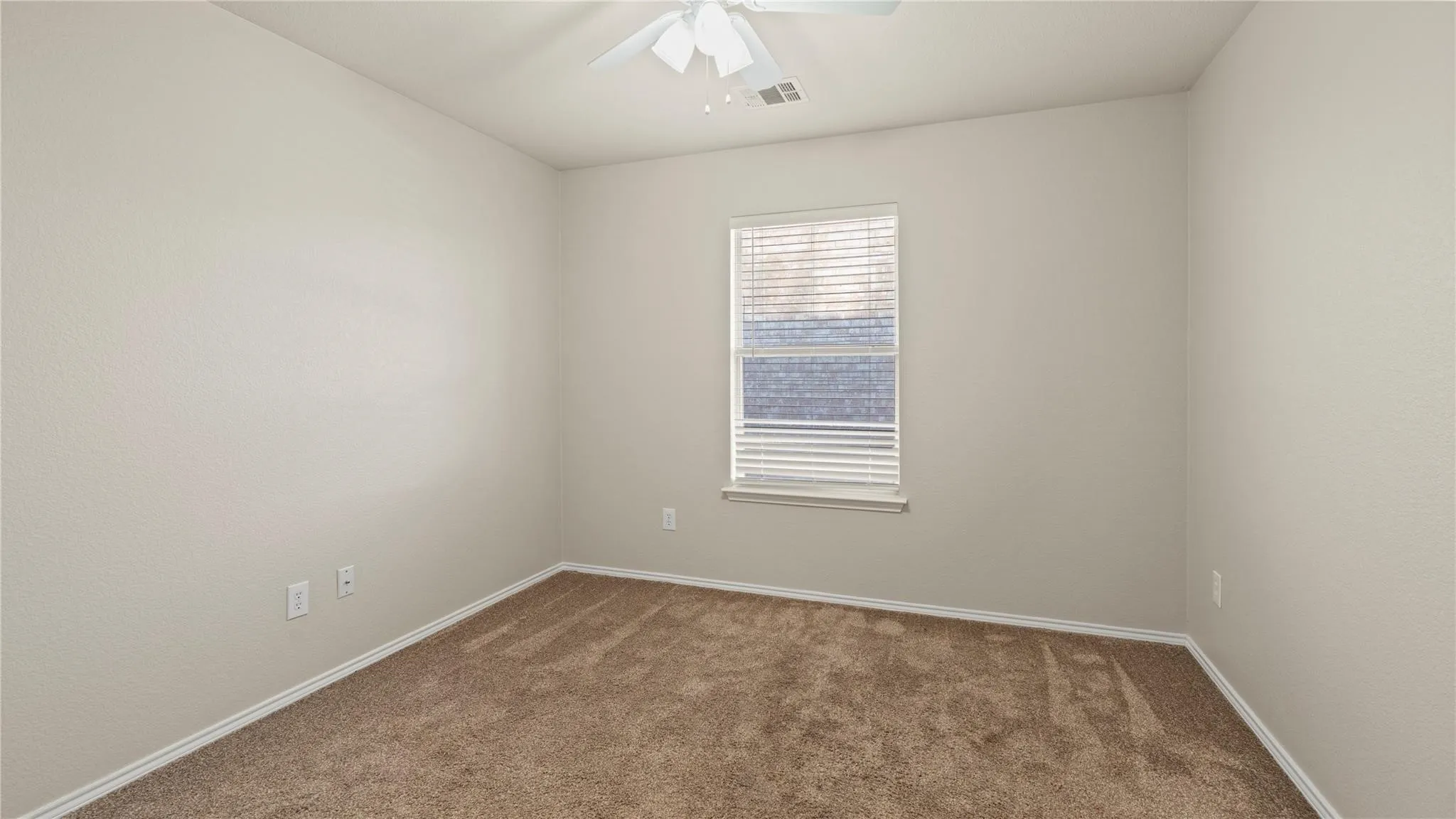 Neutral-toned walls, tan carpet flooring, and a window with horizontal blinds