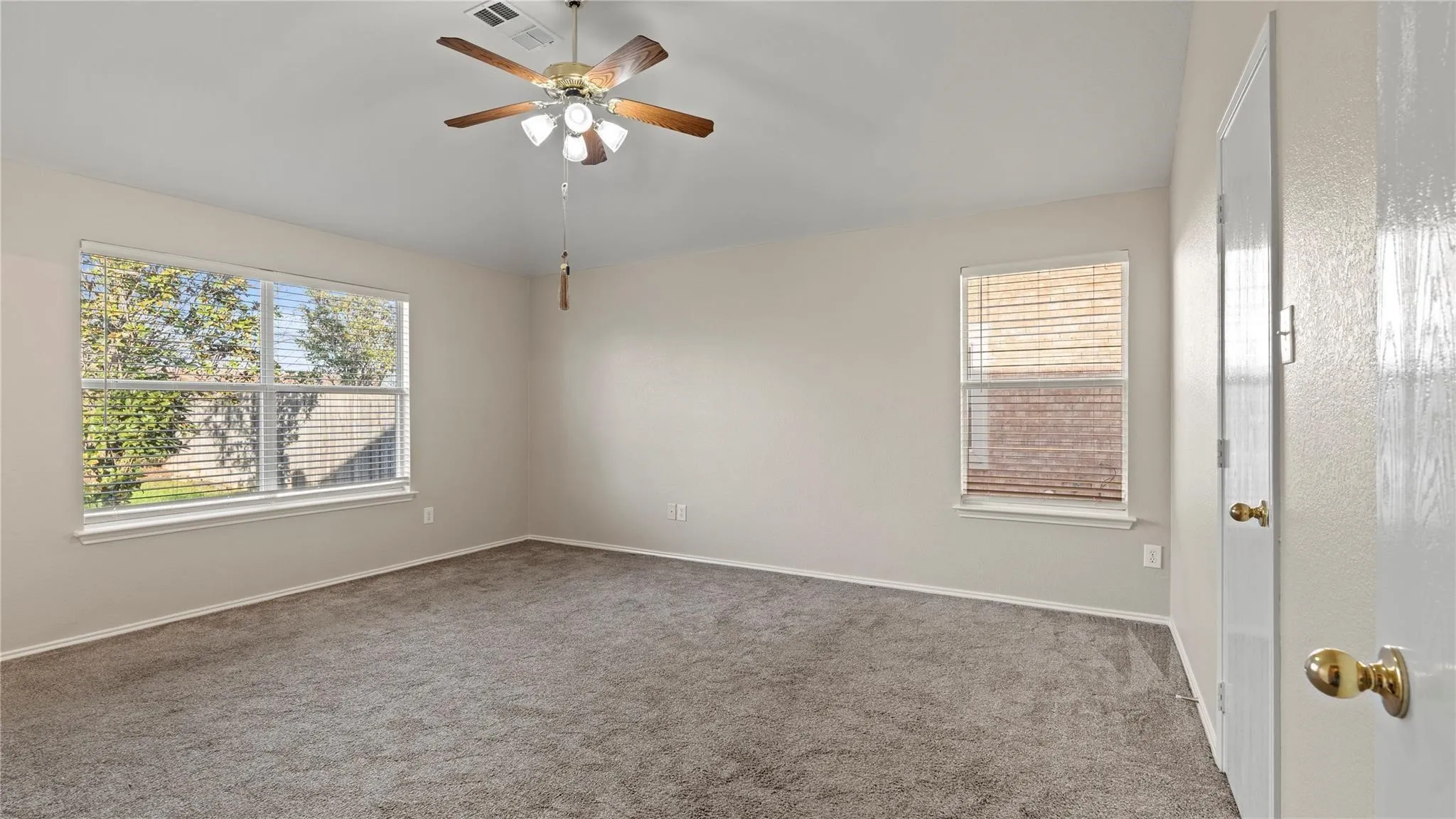 Carpeted room featuring a ceiling fan with integrated lighting, two windows, and neutral wall paint