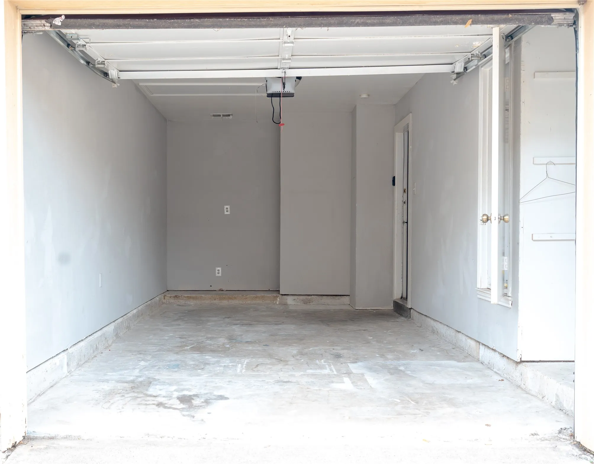 Garage with concrete flooring, light gray painted walls, and a white overhead door