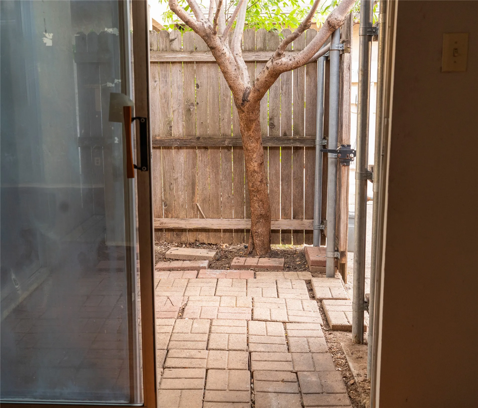 Paved patio area with brick-patterned pavers and a wood-slat fence