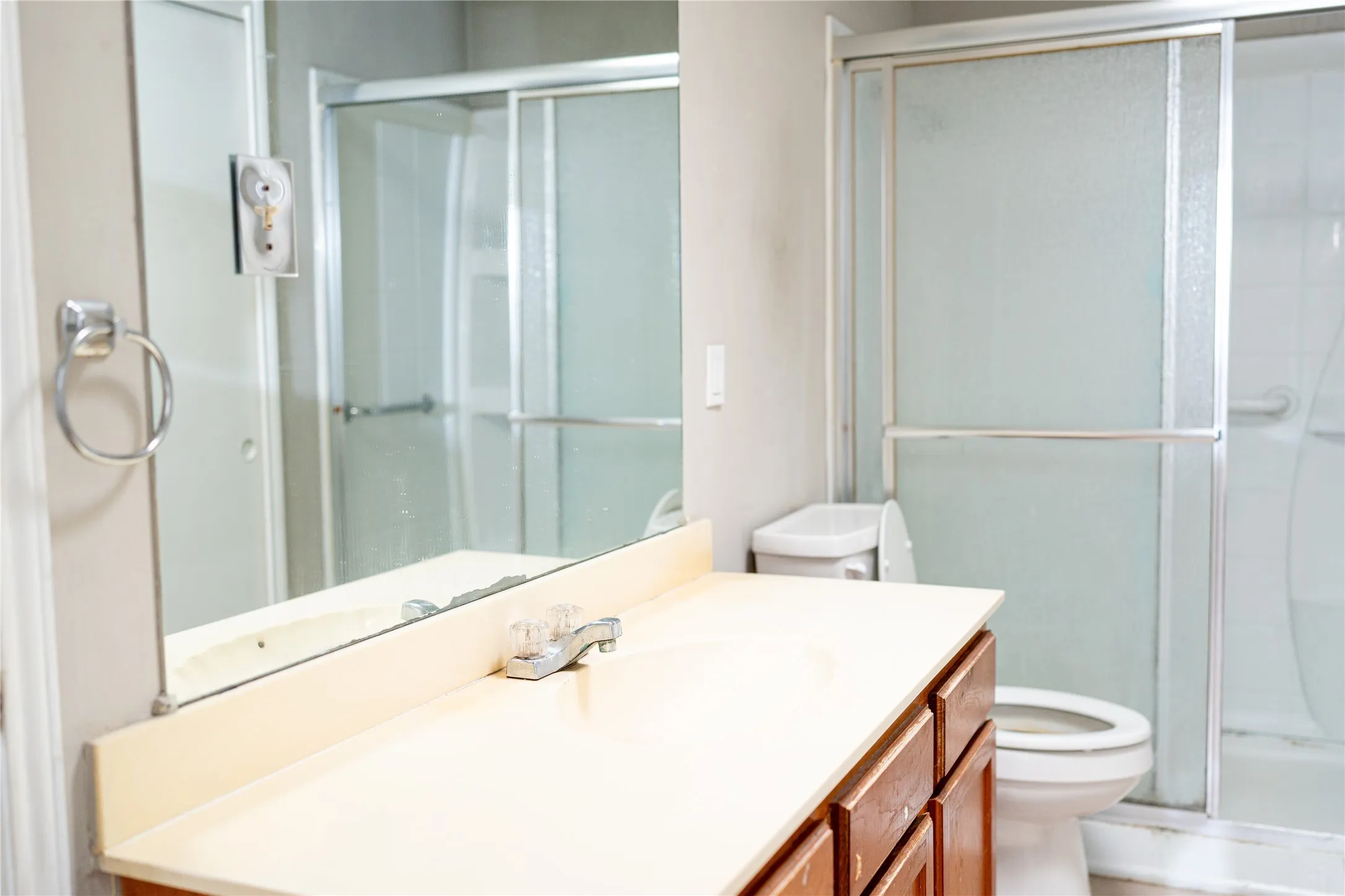 Vanity with an integrated sink, wood-finish cabinetry, and a full-width mirror
