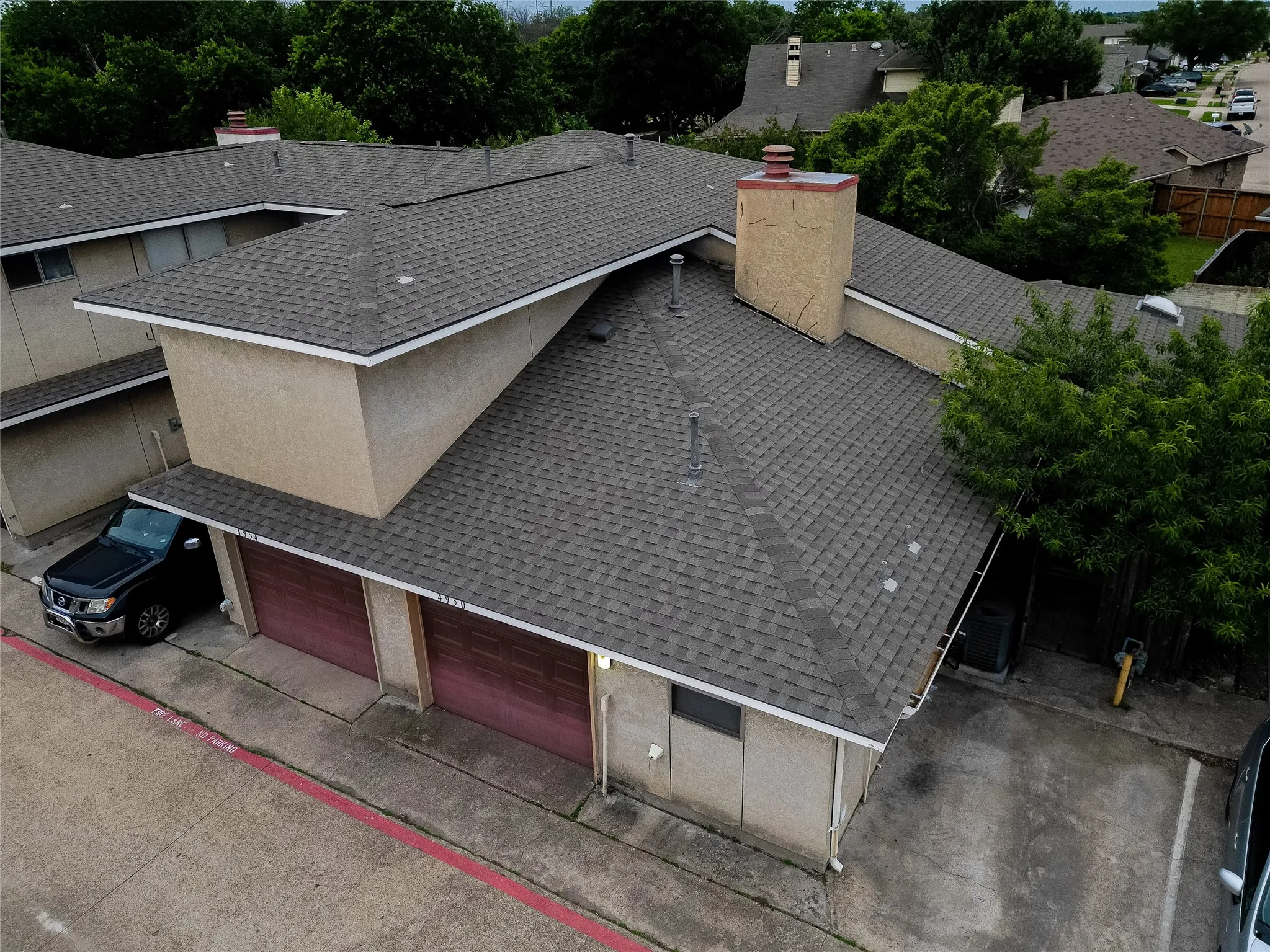 Exterior featuring a shingle roof, stucco siding, a chimney, and a two-car garage