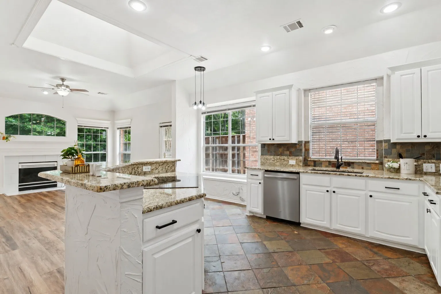Kitchen featuring white cabinetry, granite countertops, stainless steel appliances, and slate-finish flooring