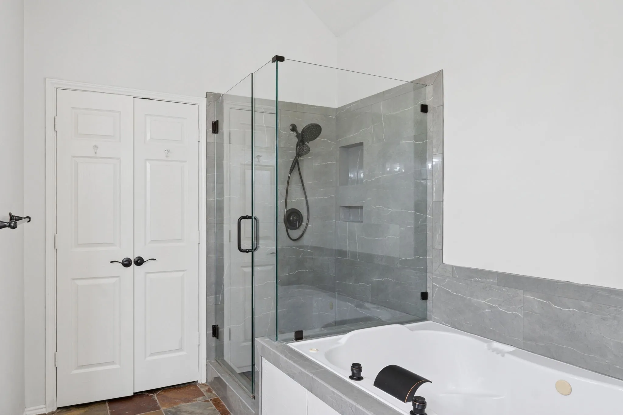 Glass-enclosed shower with gray tiled walls and a built-in niche