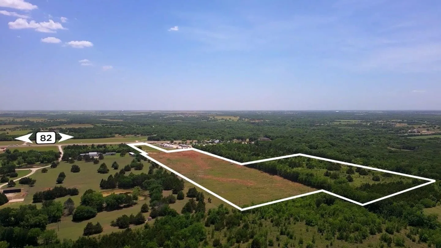 Expansive land parcel featuring clear and wooded areas, bordered by established properties and a prominent highway