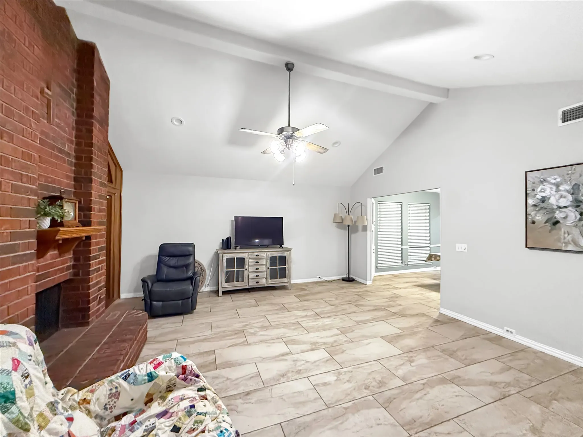 Vaulted ceiling, brick fireplace with mantel, recessed lighting, ceiling fan, and large format tile flooring