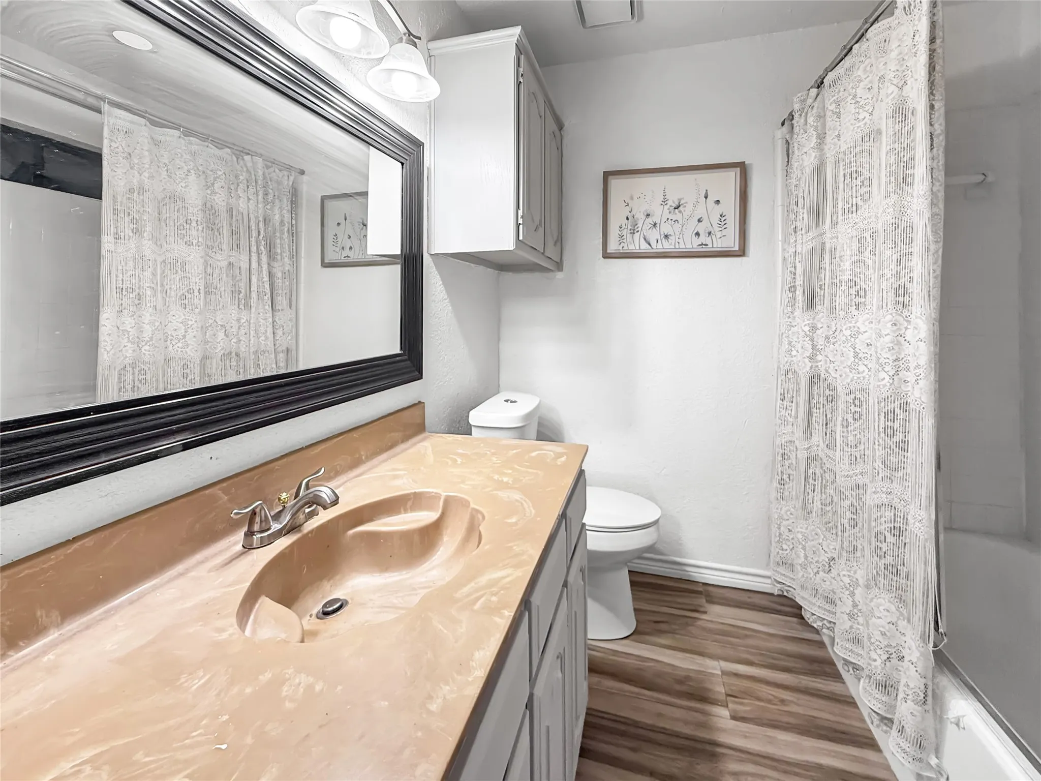 Bathroom featuring a vanity with an integrated sink, wood-finish flooring, and a built-in cabinet