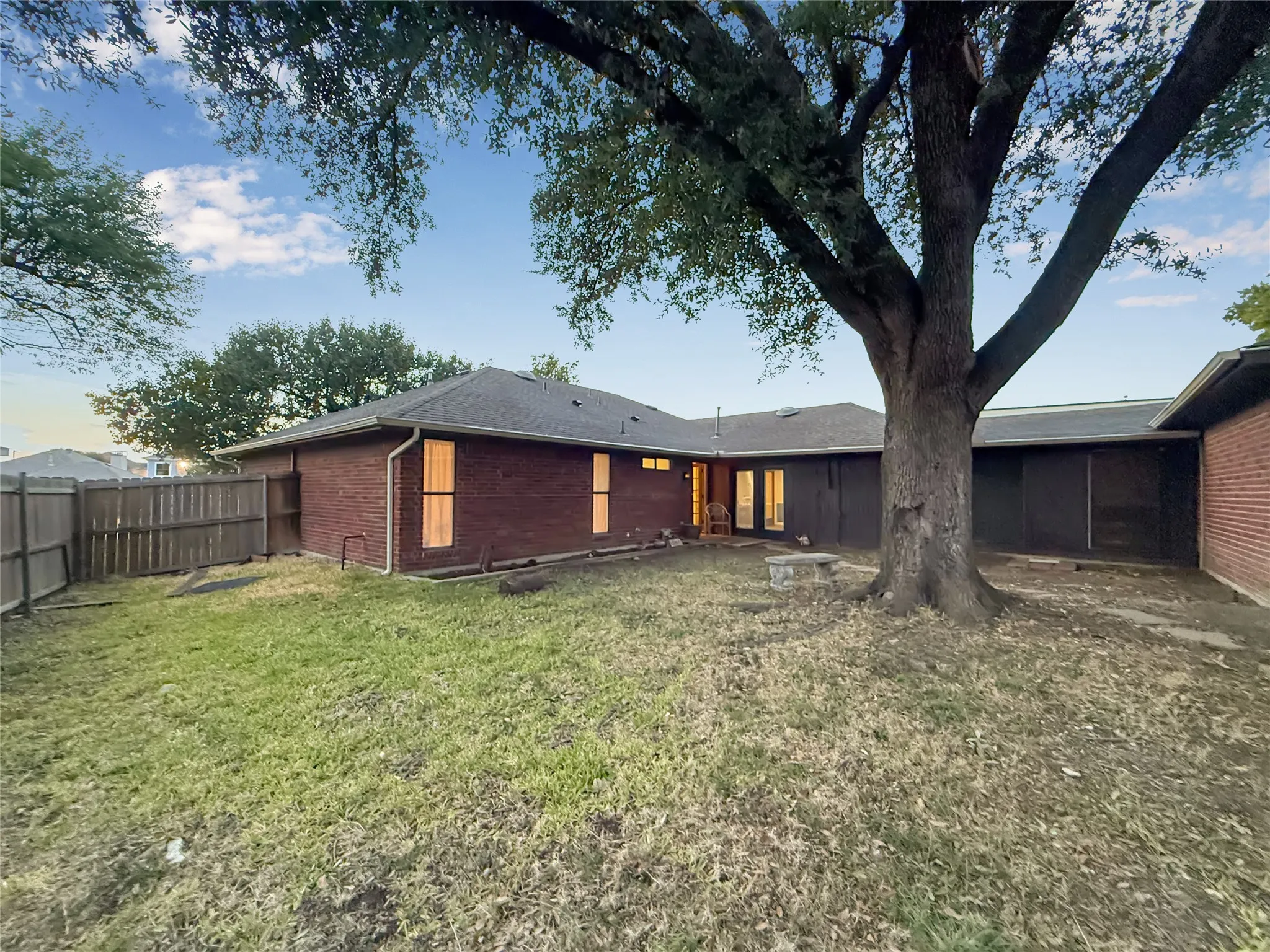 Expansive backyard featuring a mature tree, brick exterior, and a privacy fence