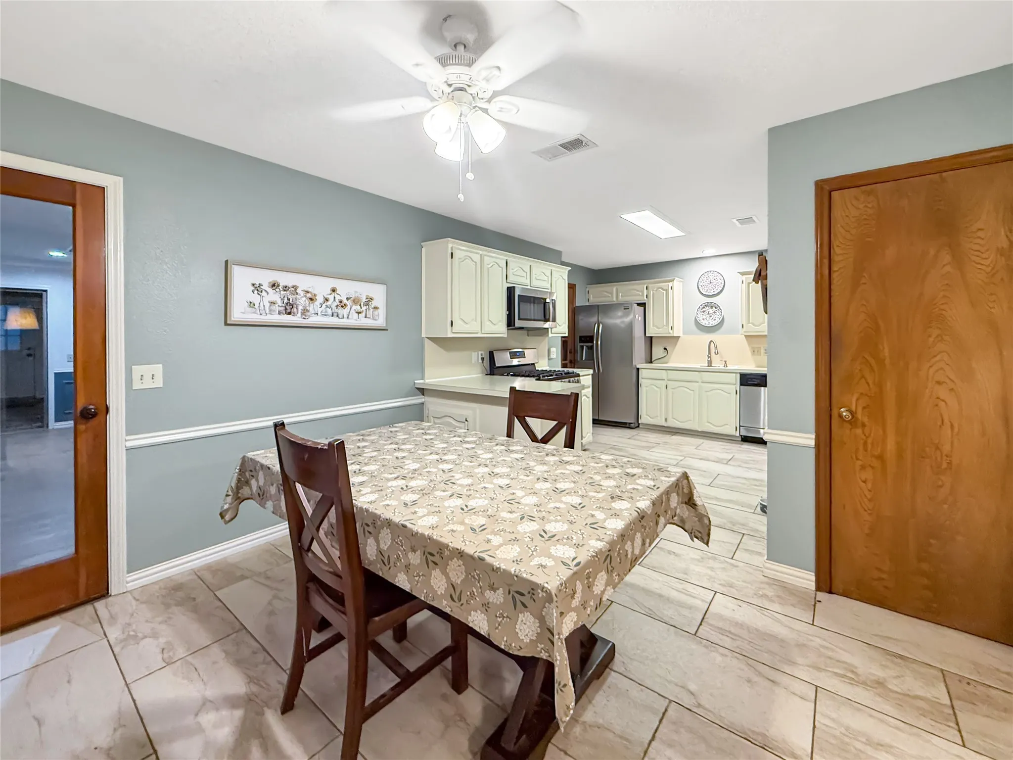 Kitchen featuring light-colored cabinetry, stainless steel appliances, and a ceiling fan