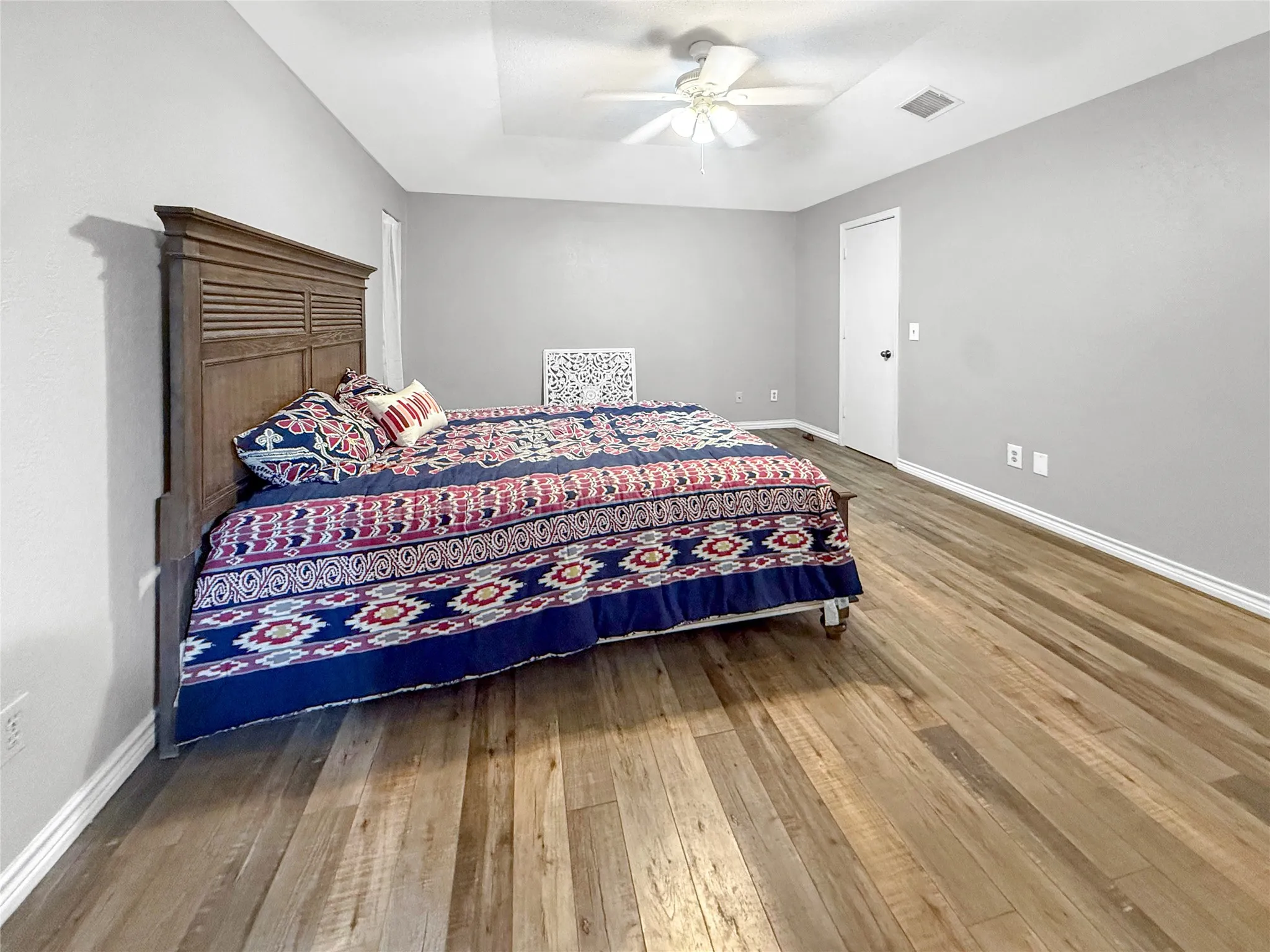 Wood-finish flooring, light gray wall paint, white trim, and a white ceiling fan with light fixture