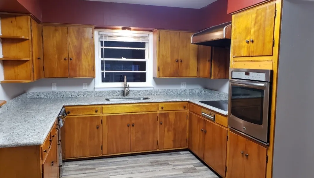Kitchen featuring sink, oven, black electric stovetop, range hood, and light hardwood / wood-style floors