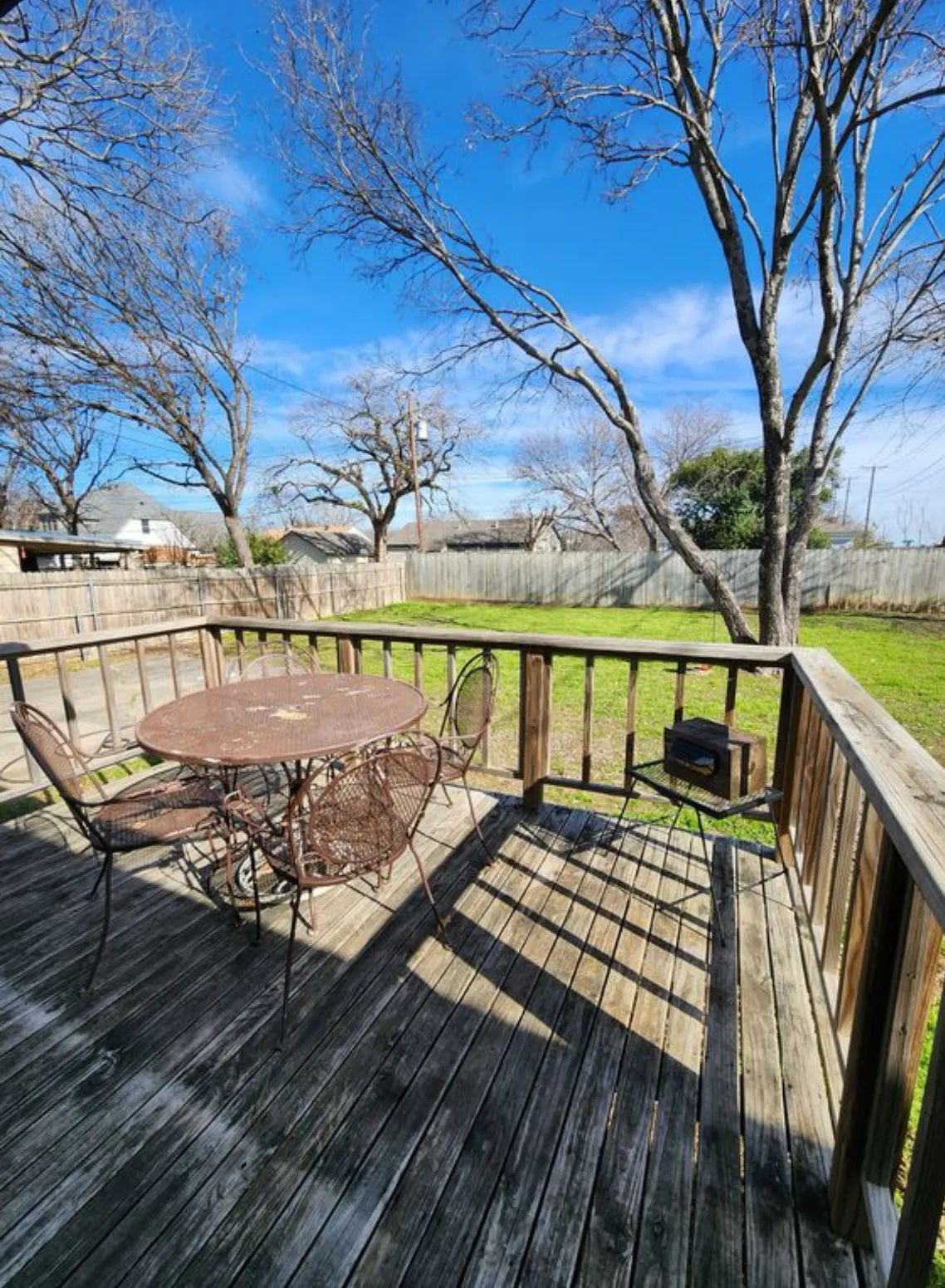 Expansive backyard featuring a wood deck, wood privacy fence, and a large grassy area