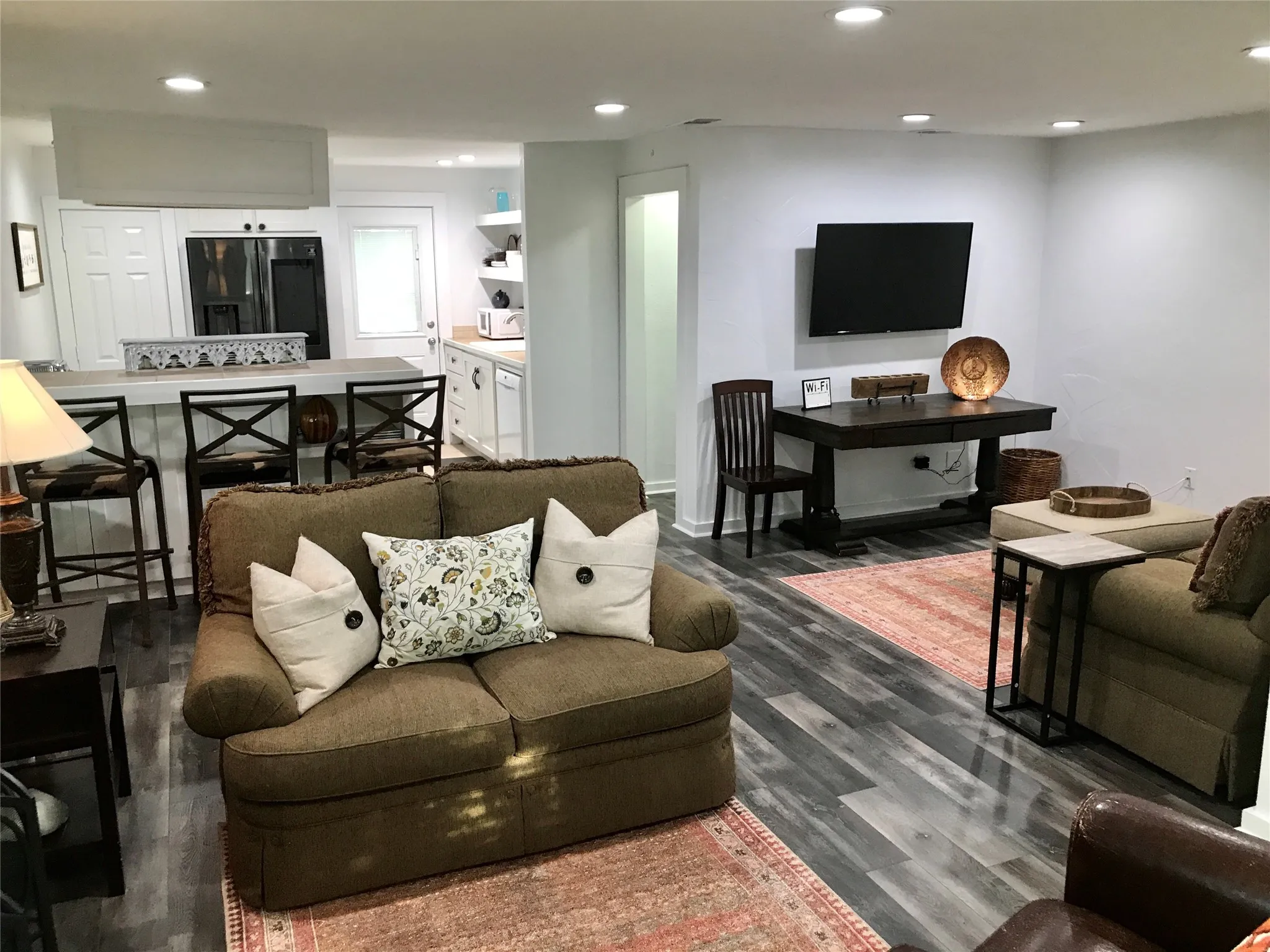 Open-concept living area with wood-finish flooring, recessed lighting, and a built-in breakfast bar with seating