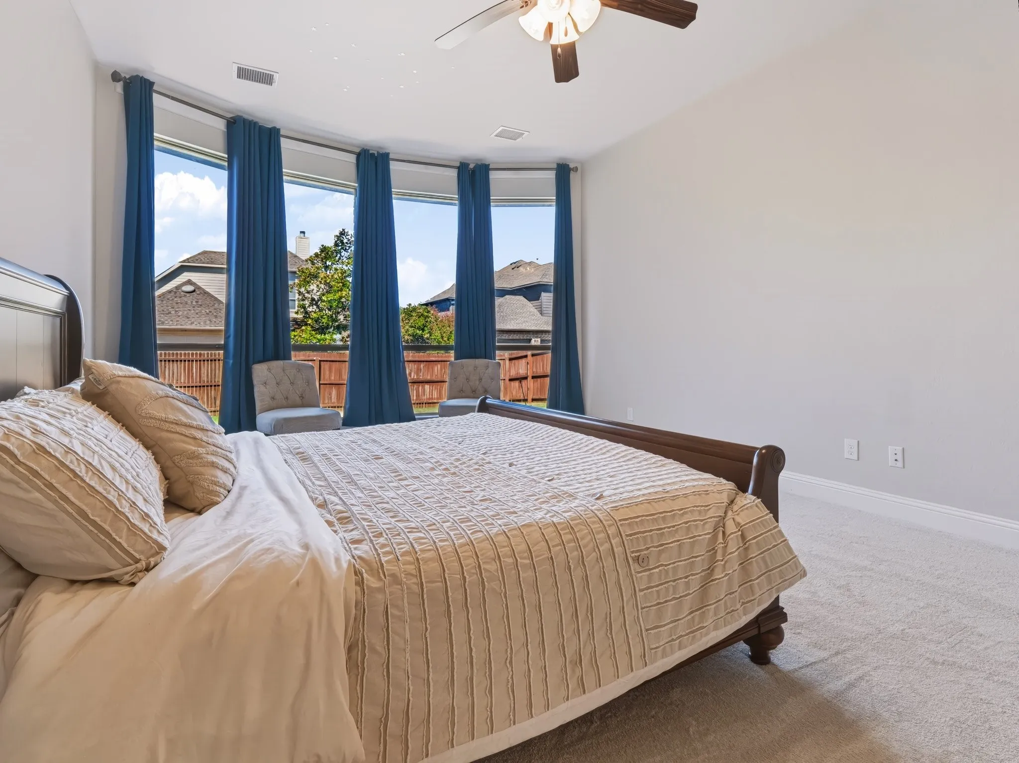 Bay window with multiple windows, ceiling fan, and light-toned carpet