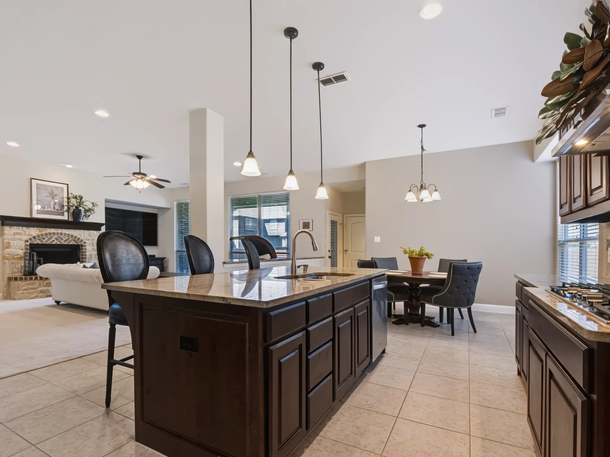 Kitchen featuring dark wood-finish cabinetry, light-toned tile flooring, and pendant lighting