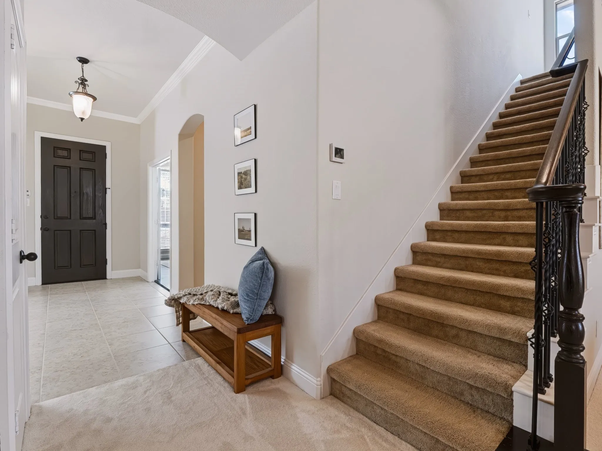 Foyer entry with tile flooring, crown molding, and an arched doorway