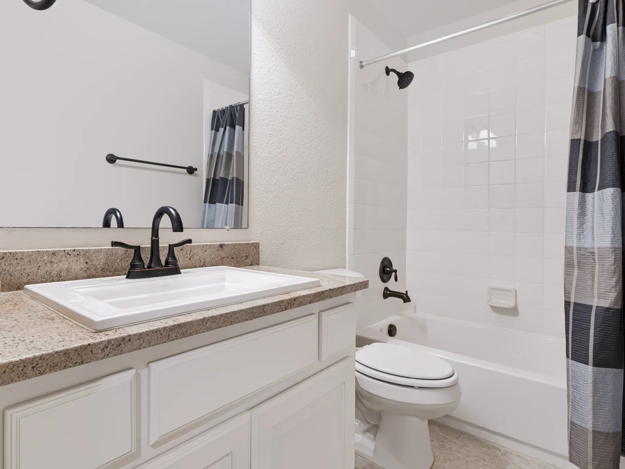 Bathroom featuring a white vanity with paneling, a rectangular sink, a speckled countertop, and oil-rubbed bronze fixtures