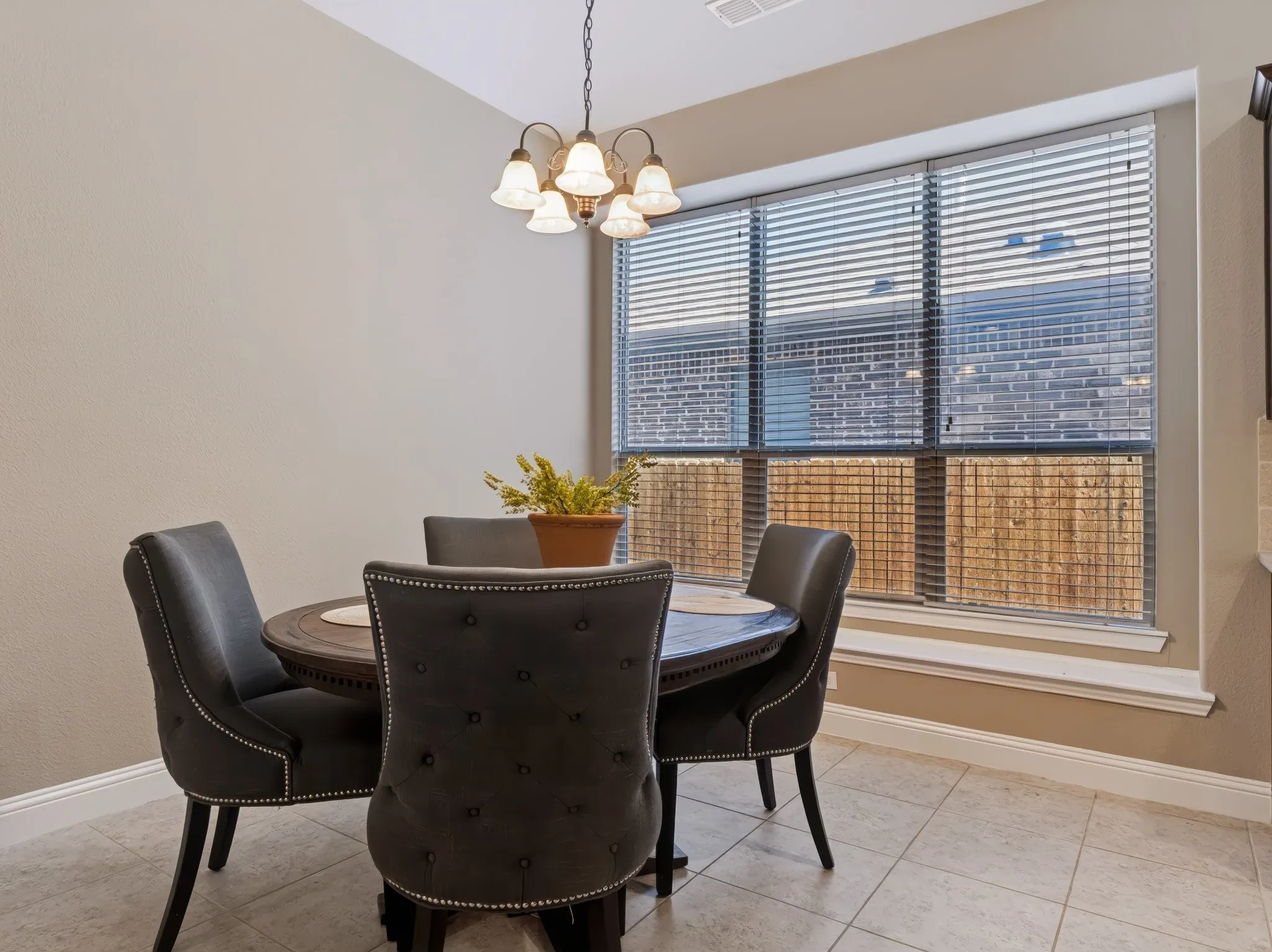 Recessed window with full blinds, tile flooring, and a decorative chandelier