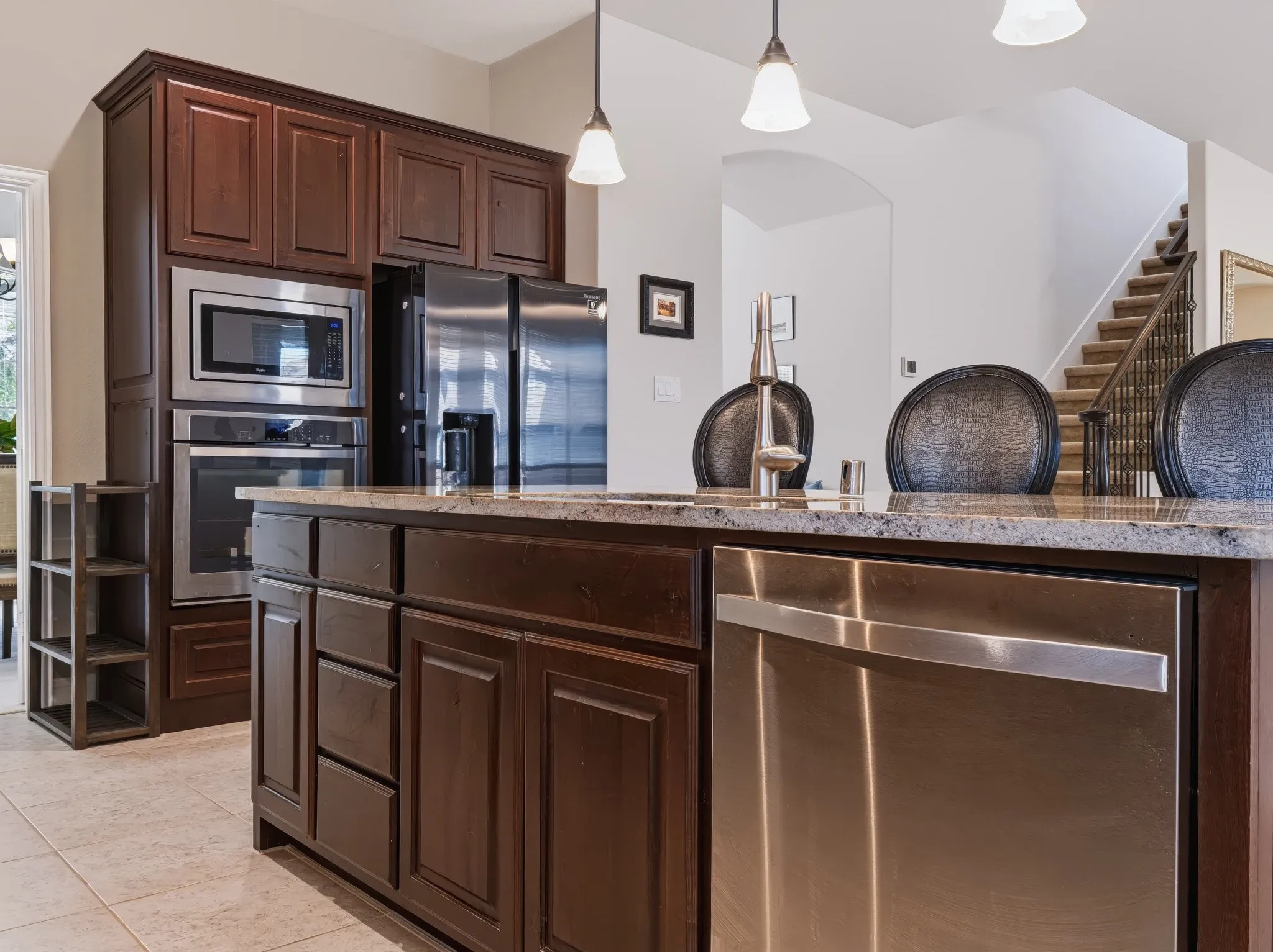Kitchen island with a light-colored countertop, dark wood-finish cabinetry, and stainless steel appliances