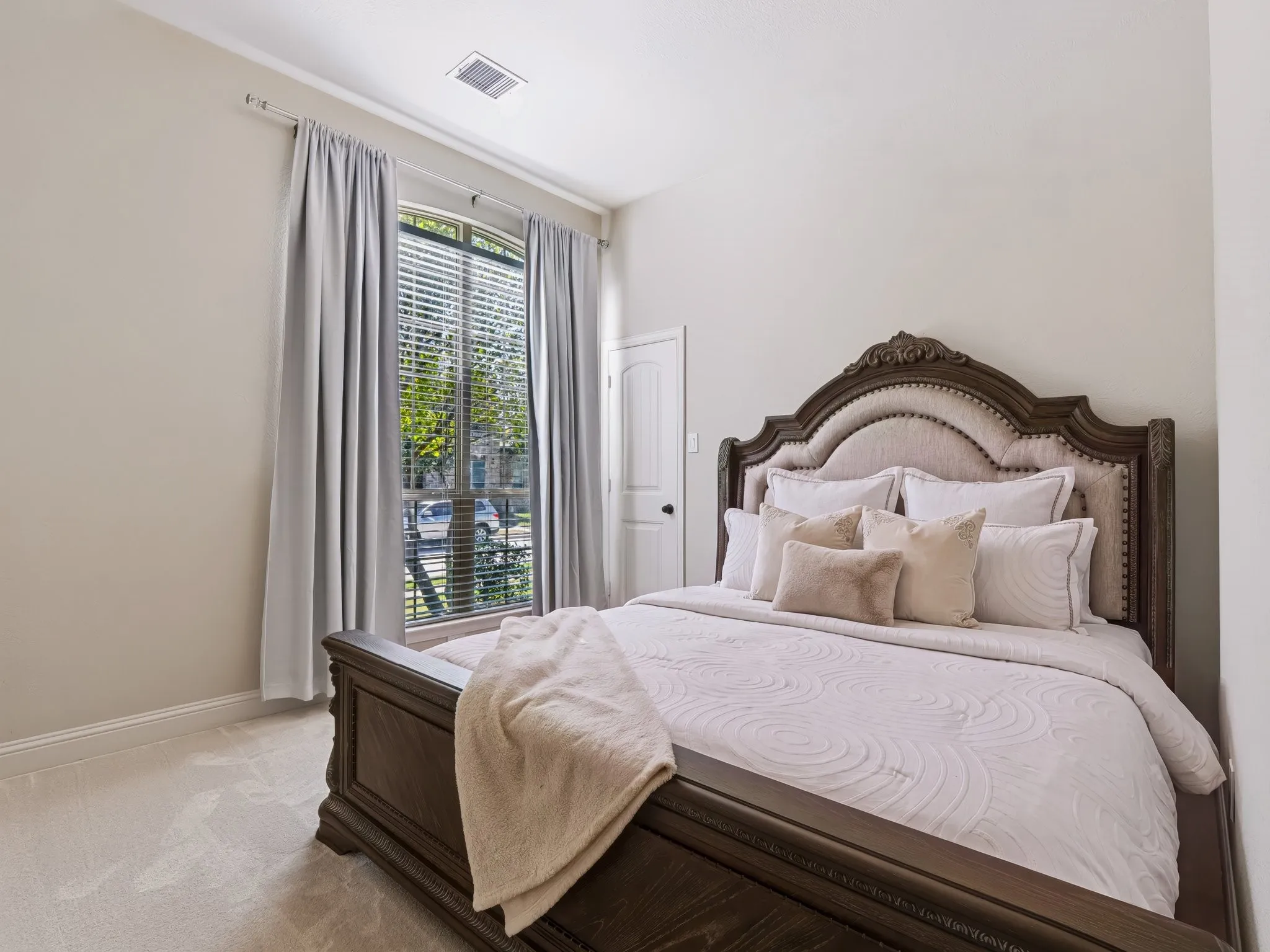 Arched window with blinds, light-toned walls, and carpet flooring