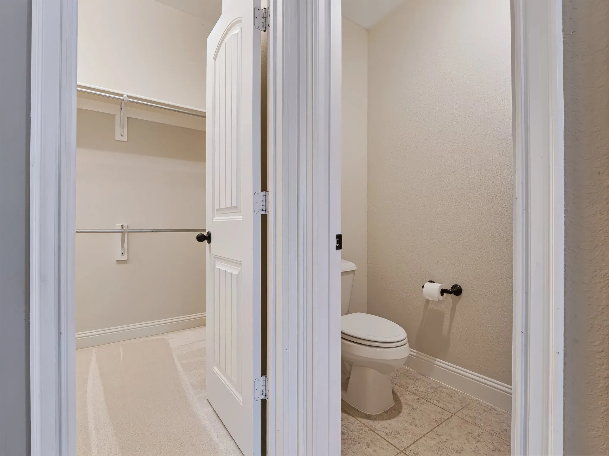 Beadboard interior door with black hardware, white baseboards, and wall-mounted shelving