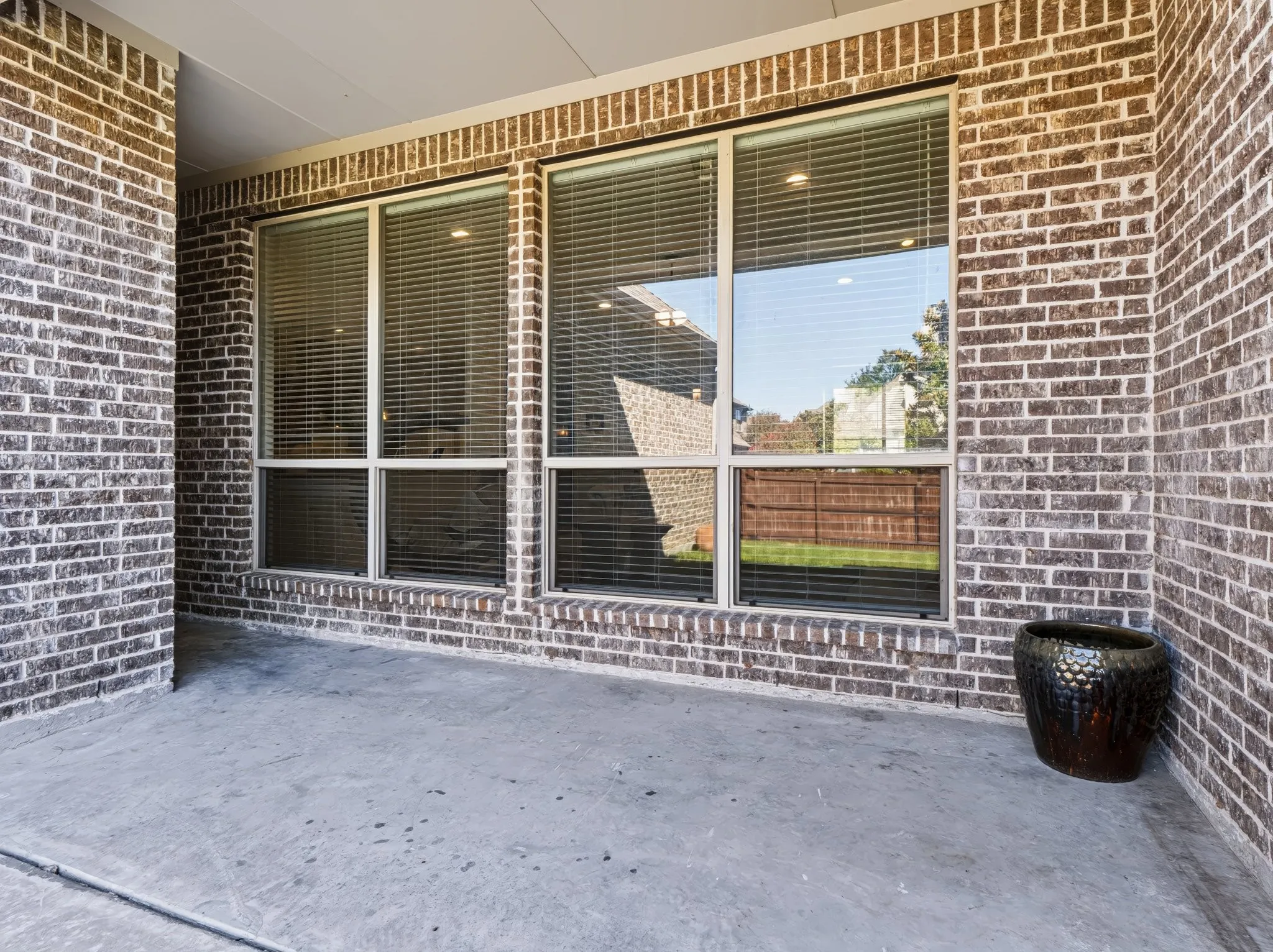 Covered concrete patio with brick exterior and large windows