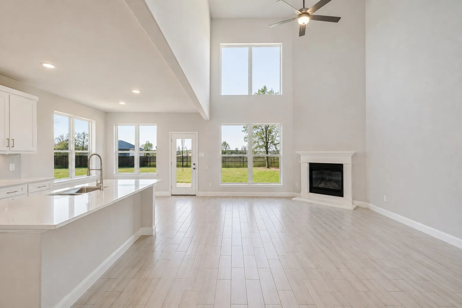 Vaulted ceilings with a ceiling fan, a fireplace with a mantel, light wood-finish flooring, and multiple windows
