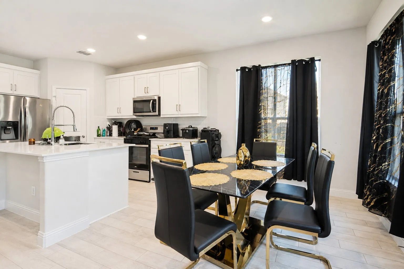 Kitchen featuring white cabinetry, stainless steel appliances, a center island with a sink, and wood-finish flooring