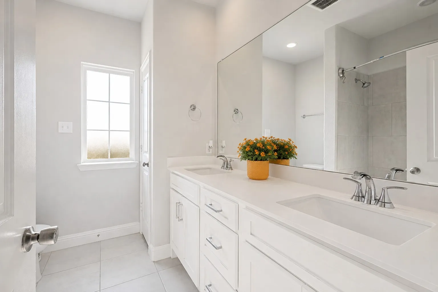 Dual vanity with integrated sinks, chrome fixtures, and a large wall-mounted mirror