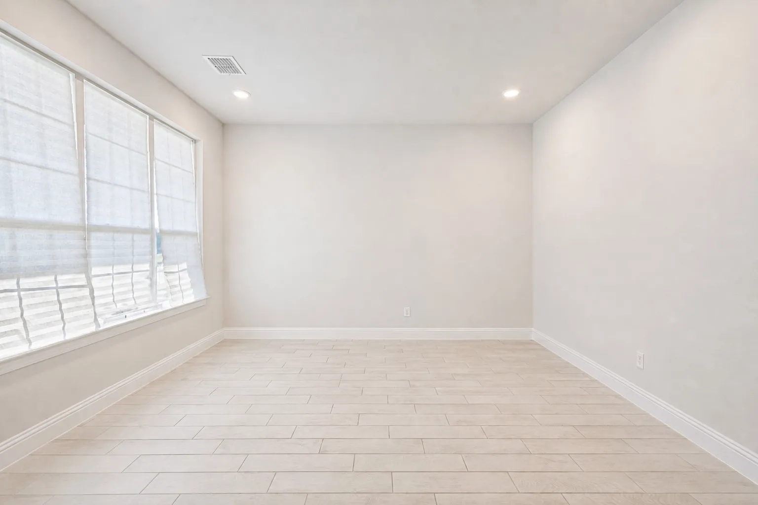 Recessed lighting with light-toned wood-finish flooring, large windows, and a neutral color palette