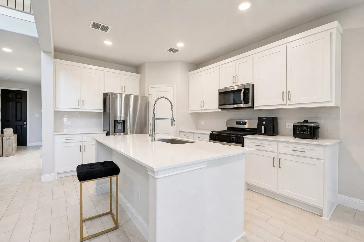 Kitchen featuring a central island, white cabinetry, integrated stainless-steel appliances, subway tile backsplash, and light wood-finish flooring
