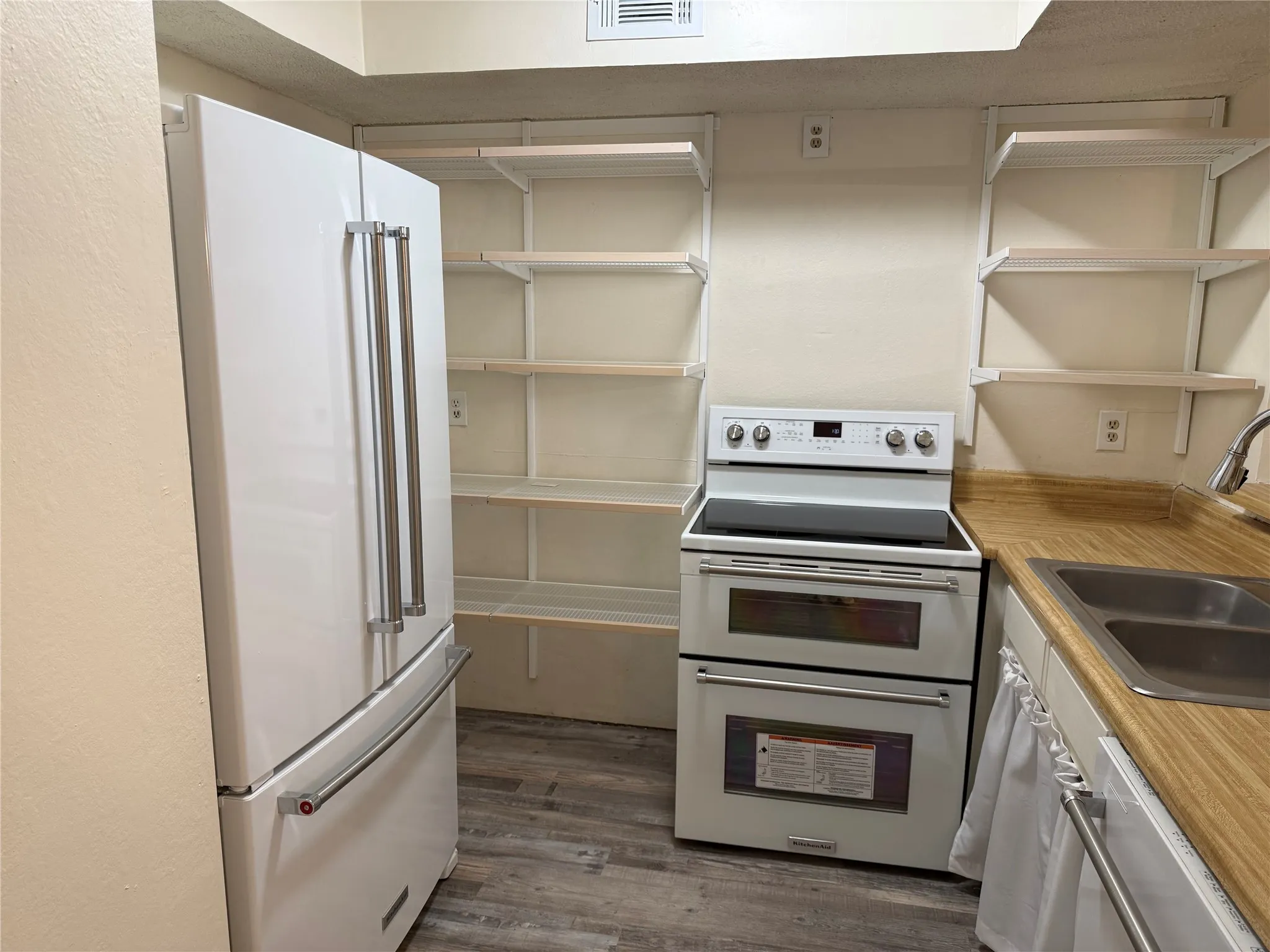 Kitchen with newer white KitchenAid appliances and new open shelving from The Container Store.