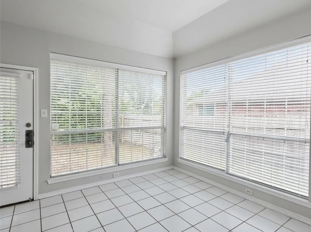 White tile flooring, multiple large windows, white window blinds, white door, and light-colored walls