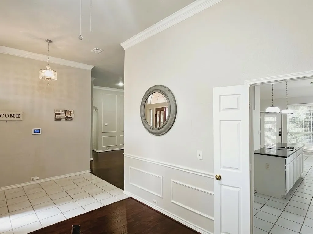 Tile flooring, wood-finish flooring, crown molding, wainscoting, and a kitchen island with pendant lighting