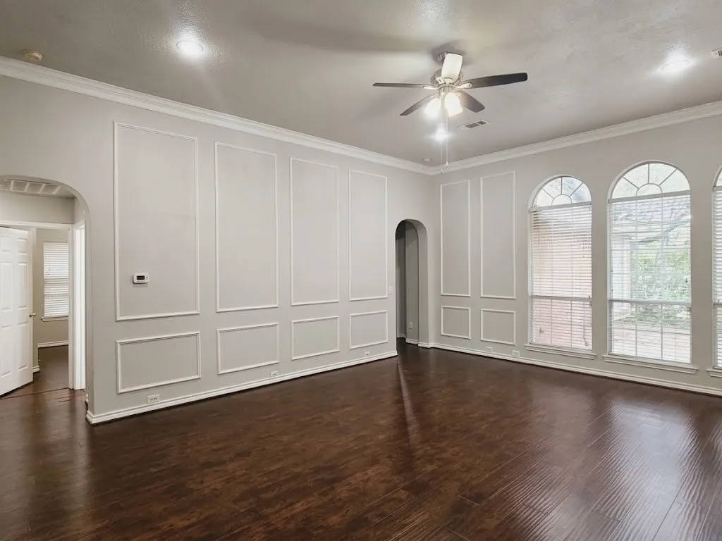 Recessed lighting, crown molding, arched windows, wood-finish flooring, and a ceiling fan