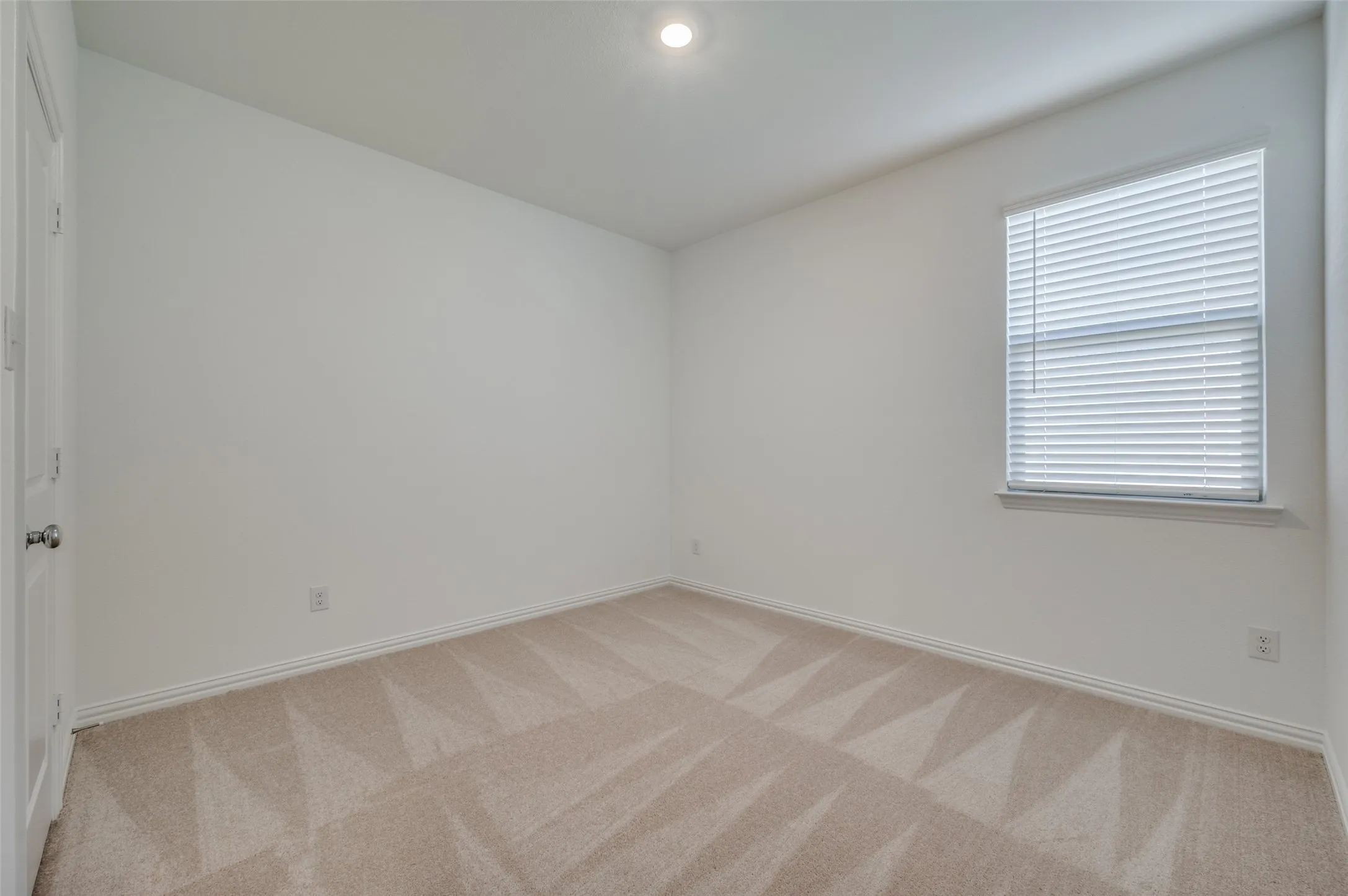 Neutral wall finishes, recessed ceiling lighting, light-toned carpet flooring, window with blinds, and white trim