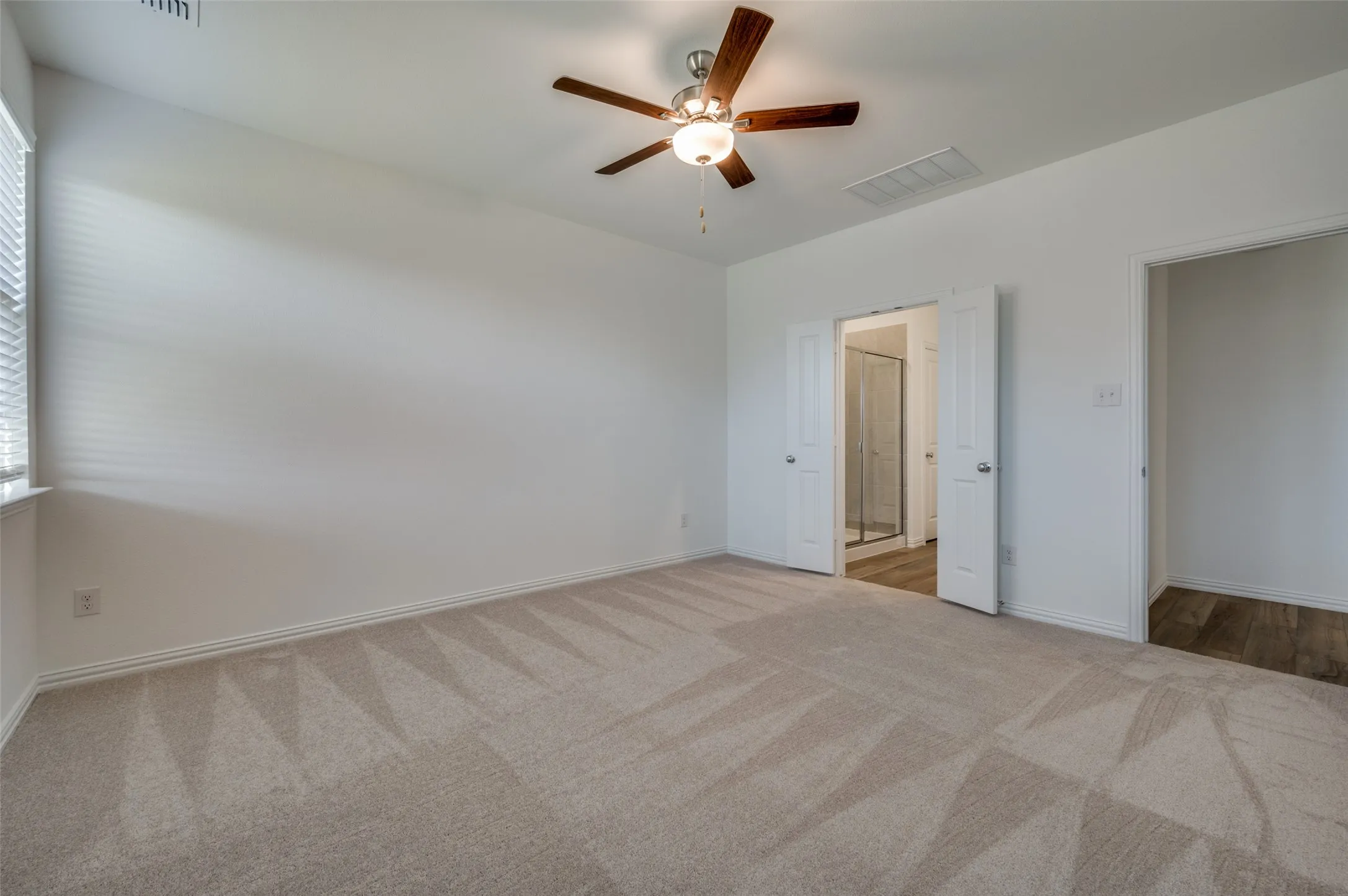 Carpeted room with a ceiling fan, window with blinds, and white interior doors
