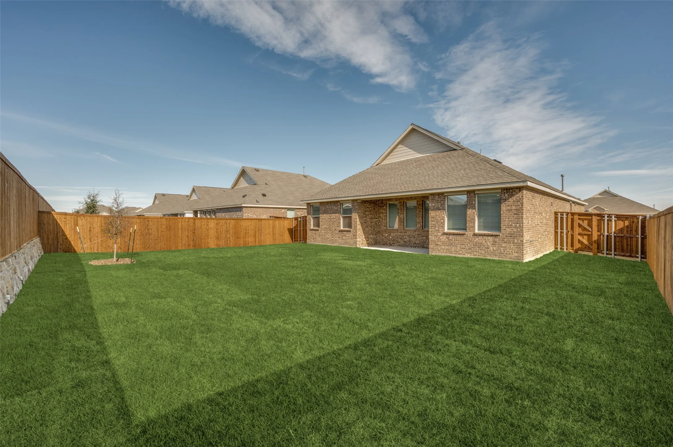 Spacious backyard featuring a manicured lawn, full wood privacy fencing, and a brick exterior