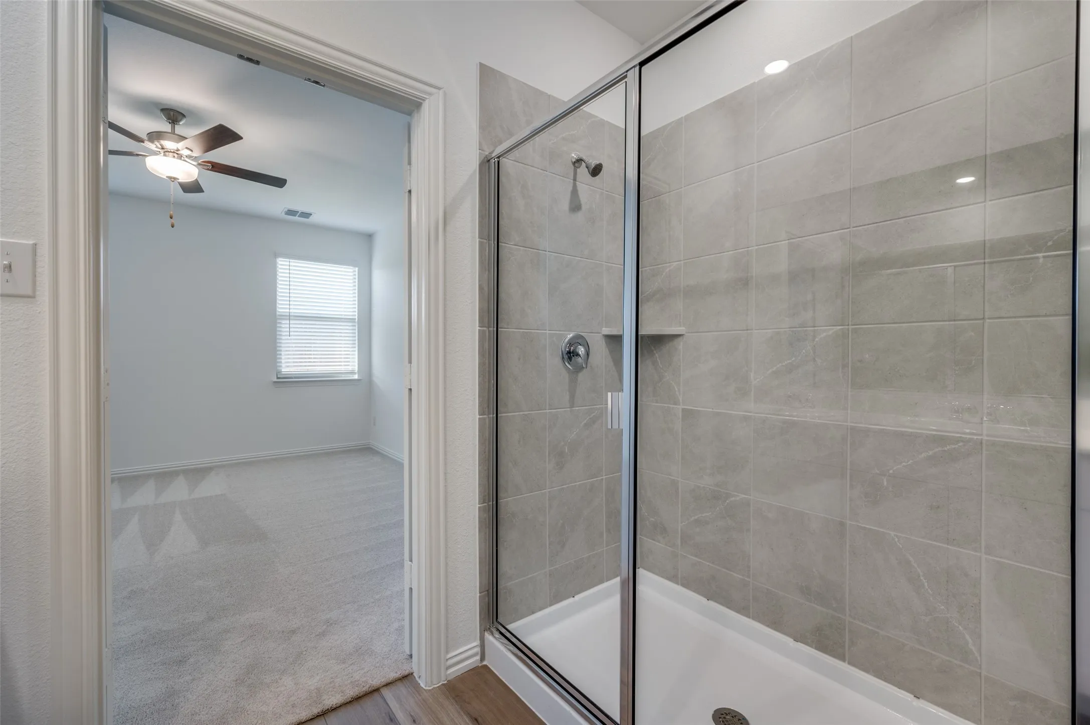 Glass-enclosed shower with gray tiled walls and a built-in shelf