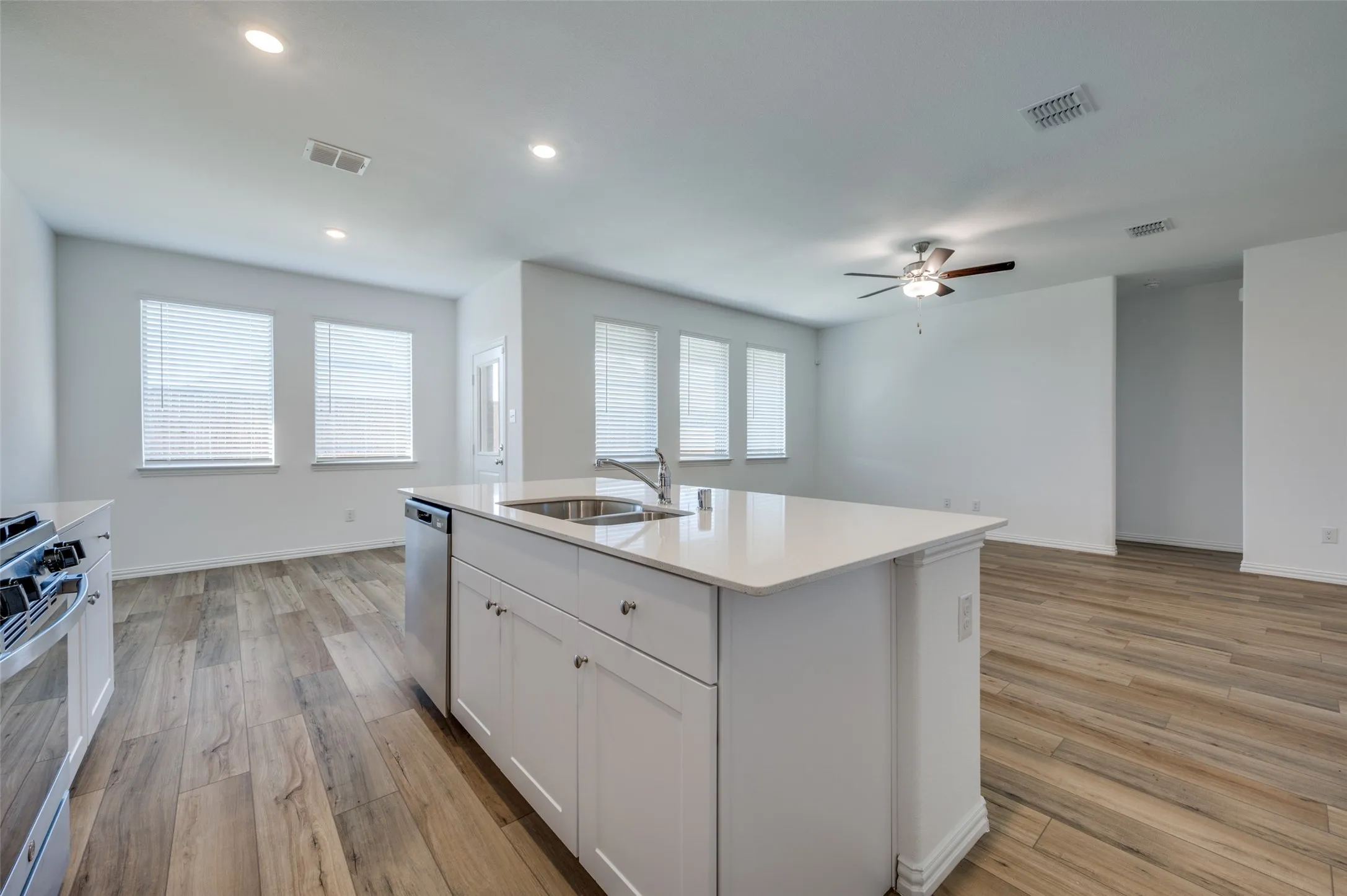 Kitchen island with white cabinetry and integrated stainless steel dishwasher, featuring a single basin sink and a high-arc faucet