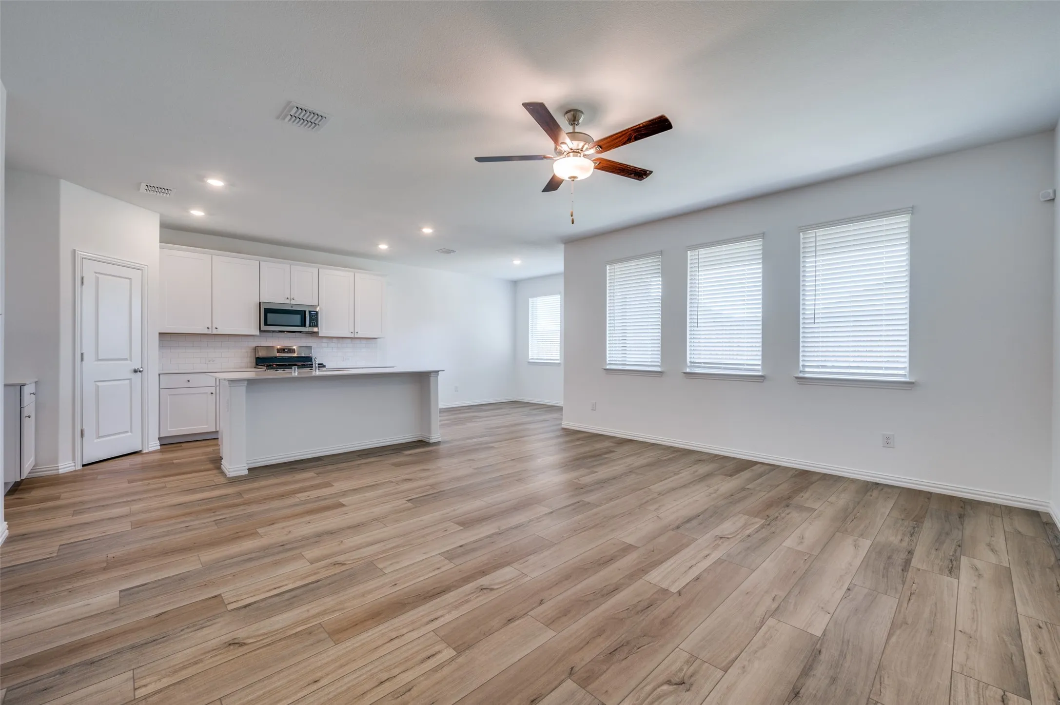 Open-concept living space featuring wood-finish flooring, recessed lighting, and a ceiling fan