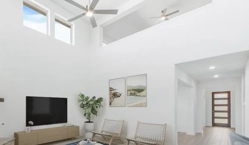 Living area with ceiling fan, a high ceiling, light wood-style floors, and beamed ceiling