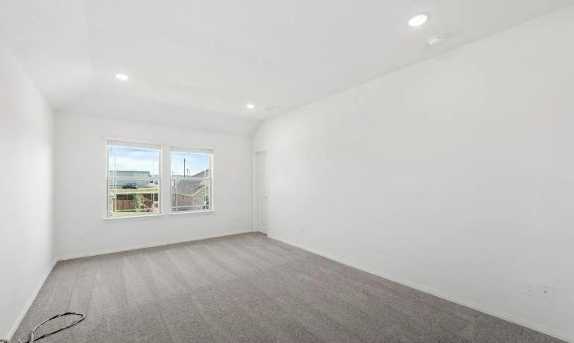 Empty room with recessed lighting, carpet floors, vaulted ceiling, and a smoke detector
