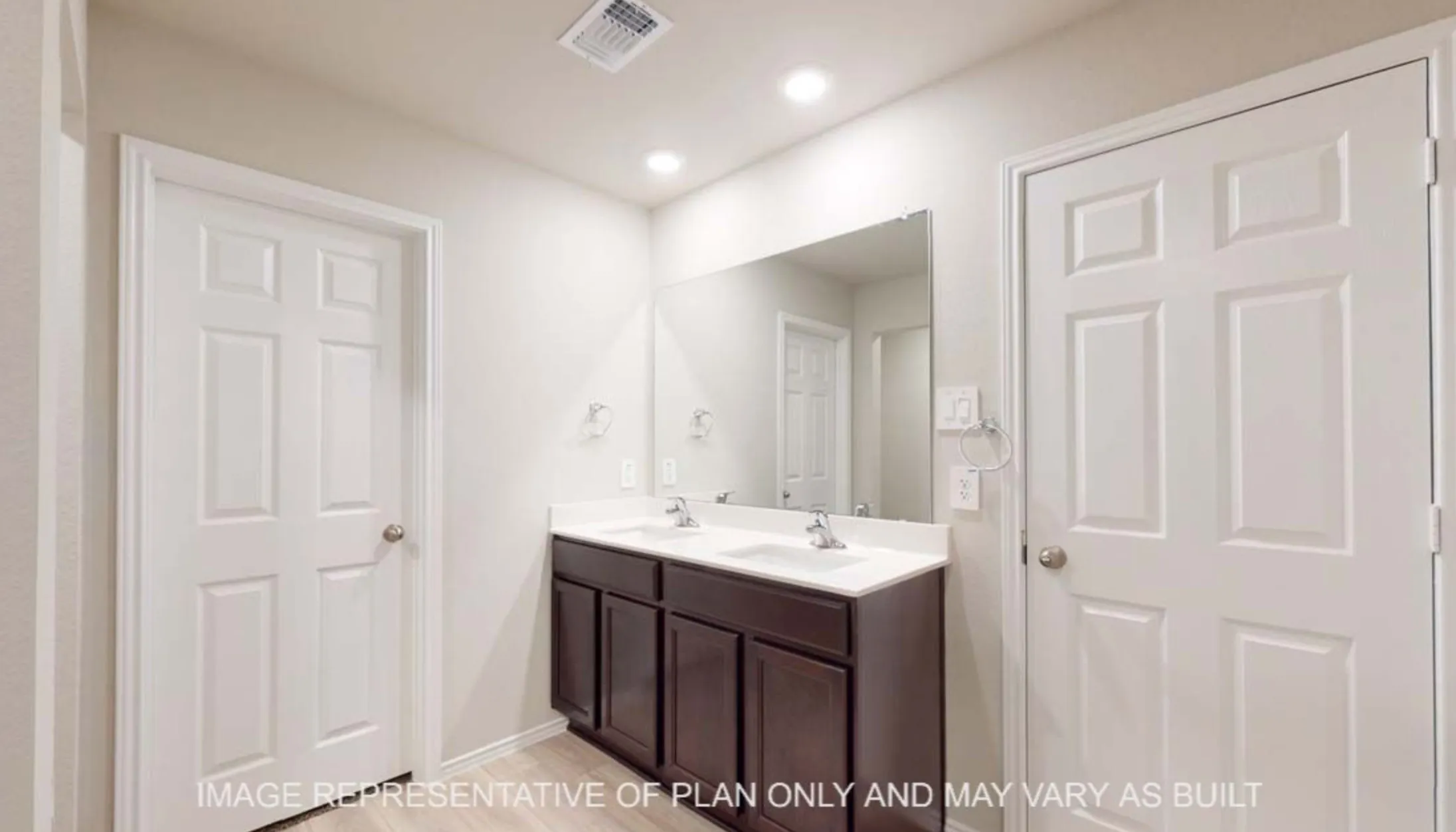 Dual vanity with dark wood-finish cabinetry, integrated sinks, and a large wall-mounted mirror