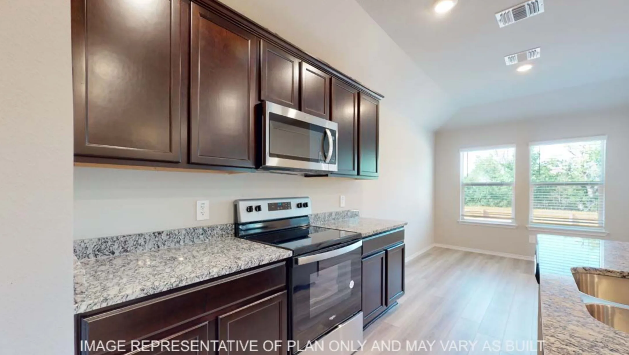 Kitchen featuring dark wood cabinetry, light speckled countertops, stainless steel appliances, and wood-finish flooring