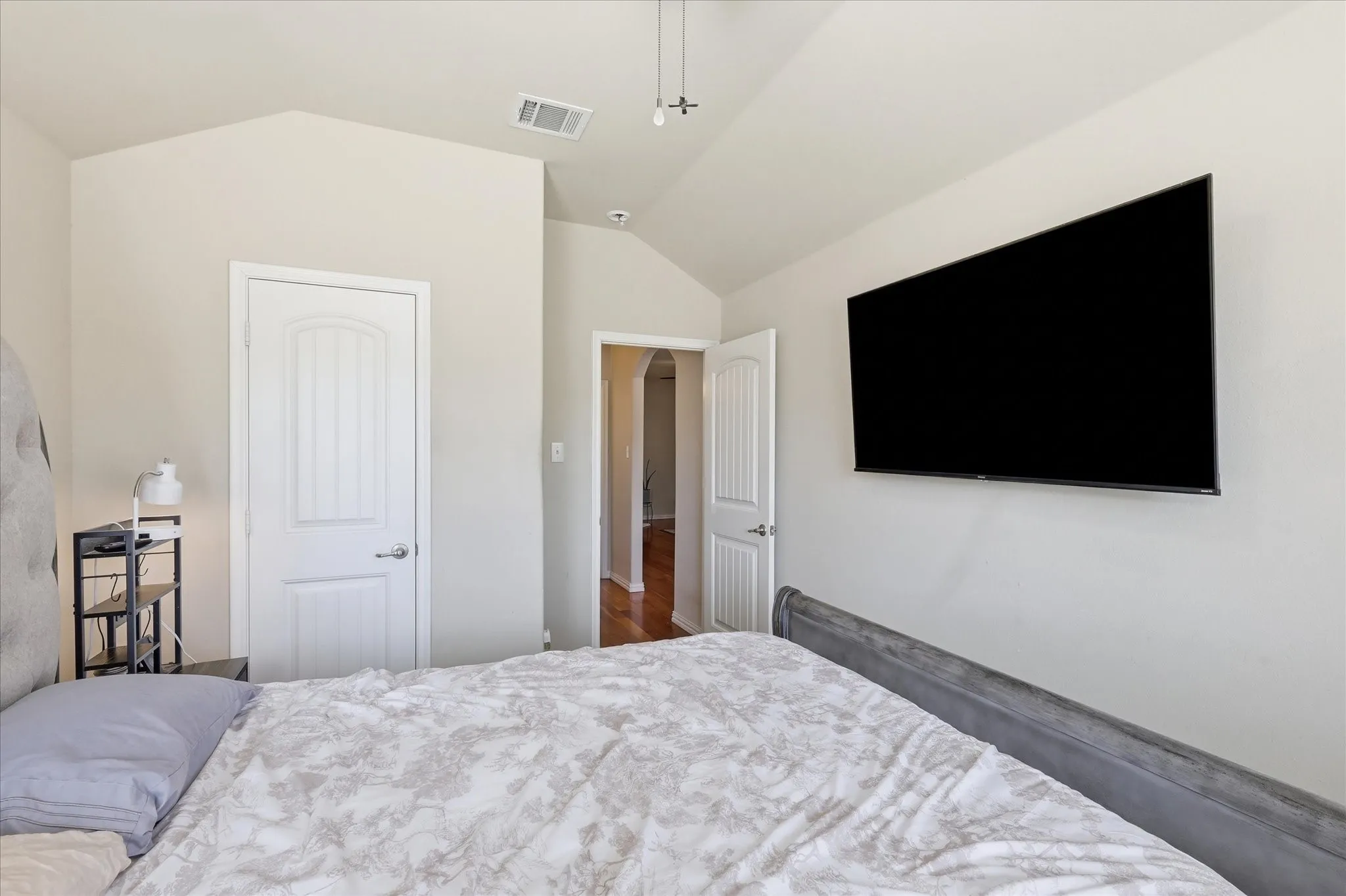Vaulted ceiling with an overhead light fixture, white interior doors, and light-colored wall paint